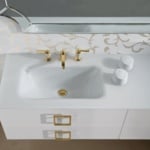White ceramic bathroom sink with gold faucet and drawers