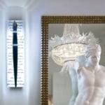 Wall sconce with metal fixture mounted on glass panel