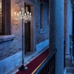 Glass chandelier floor lamp with metal stand in a brick corridor