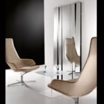Beige fabric swivel lounge chairs with metal bases beside glass table