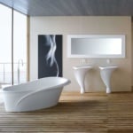 Freestanding white bathtub and wall-mounted sinks in tiled bathroom