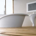 White freestanding bathtub and pedestal sink with curved design in bathroom