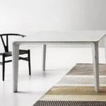 Rectangular marble dining table with black wooden chair on woven rug