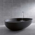 Freestanding round black bathtub with matte finish in tiled bathroom