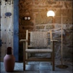 Metal floor lamp with spherical shade beside wooden chair in rustic room