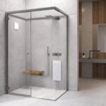 Glass sauna and steam room enclosure with metal frame and wooden seat in bathroom setting