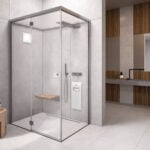 Glass steam room and sauna enclosure with metal frame and wooden seat in bathroom setting