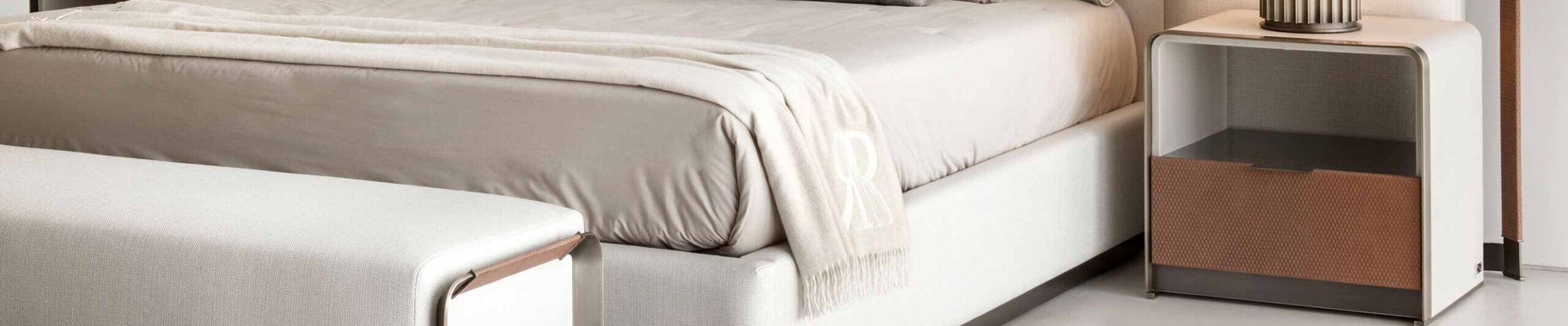 Fabric upholstered bedside table with wood drawer beside bed