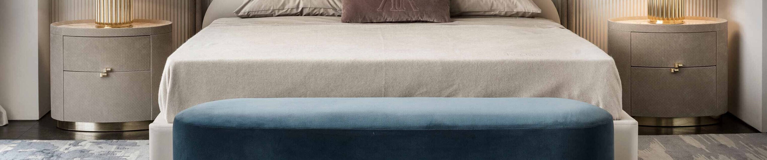 Round bedside tables with textured wood finish beside upholstered bed