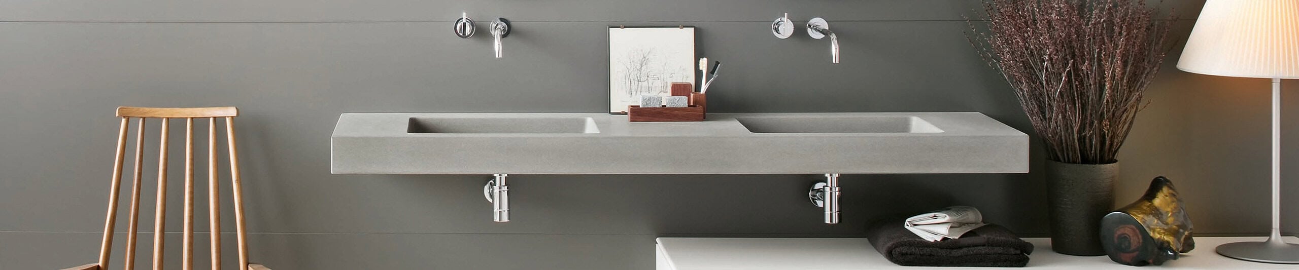 Wall-mounted double concrete sink with chrome faucets in bathroom setting
