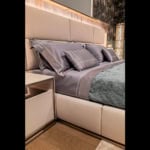 Leather storage bed with upholstered headboard and side table in bedroom setting