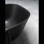 Black resin bathtub in bathroom setting.