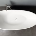 White resin bathtub with chrome faucet on gray floor